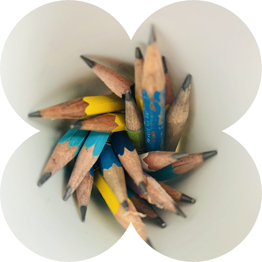 Small sharpened pencils tucked into a white cup.